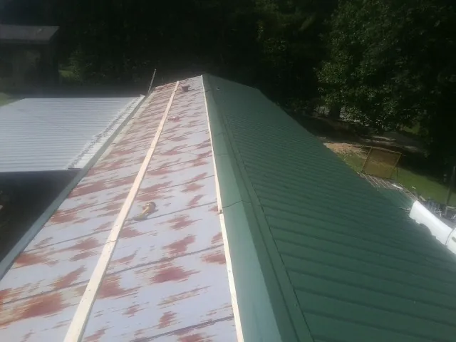 Old rusted panels beside newly installed green metal roofing — Wind Damage Roof Repair by Roofing Brothers in Carleton